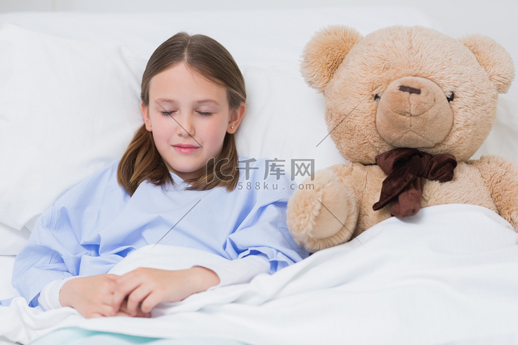 孩子躺在床上和泰迪熊一起睡觉