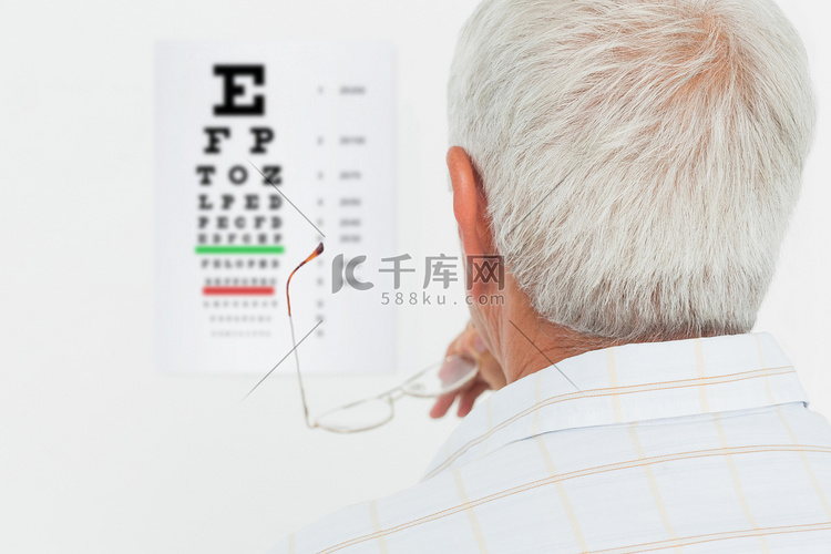 看视力检查表的老人的背面图