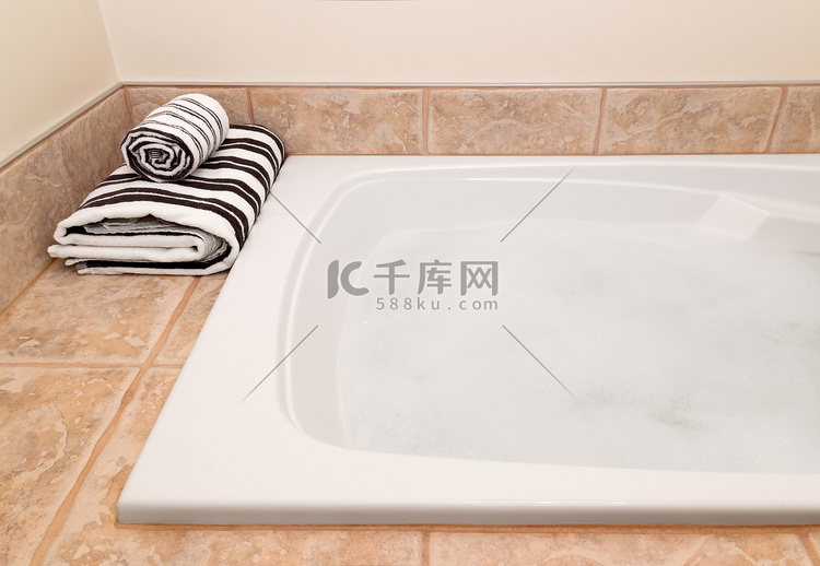折叠条纹毛巾和带泡沫的浴缸