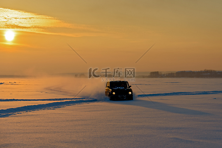 汽车在夕阳的余晖中驶过结冰的河