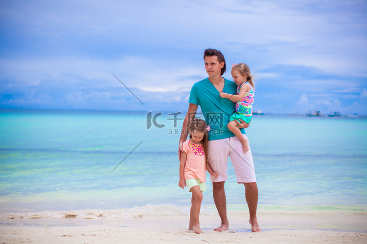 走在海边的年轻父亲和他的两个小