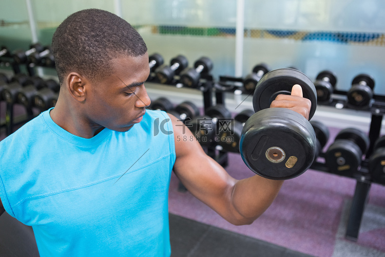 年轻人在健身房用哑铃锻炼