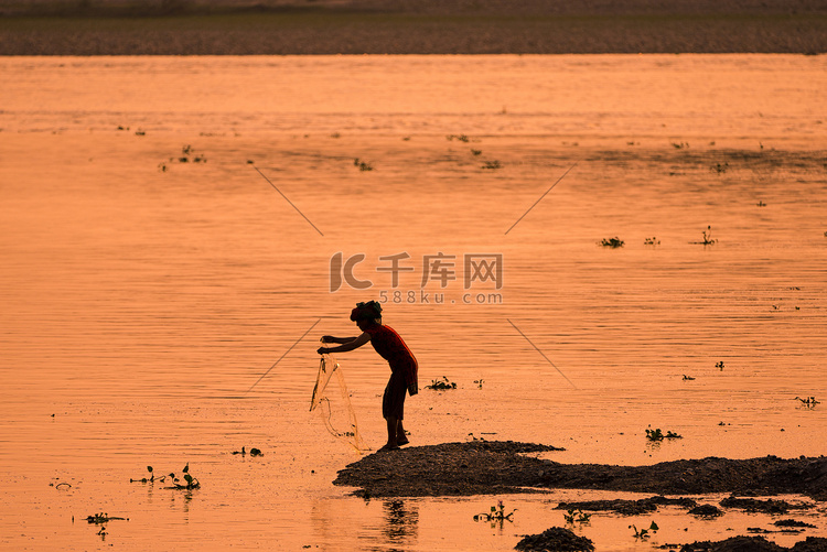 亚洲女人在河里钓鱼，夕阳下的剪