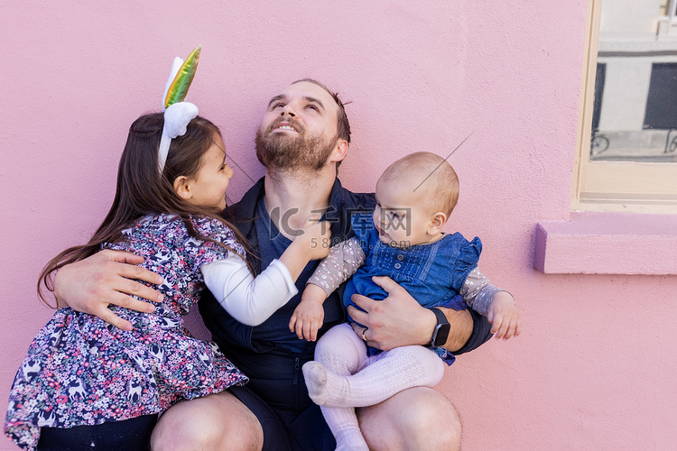 快乐的父亲在粉红色的墙前拥抱他