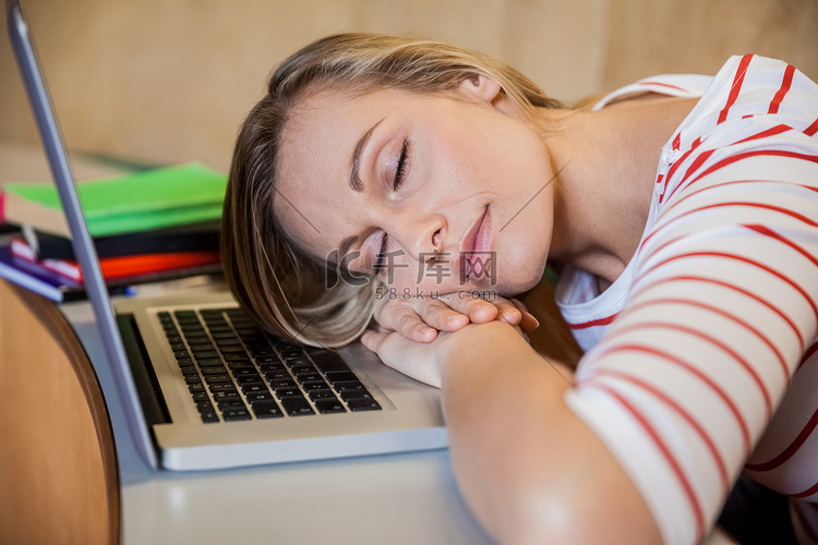 女学生在课堂上用笔记本电脑睡觉