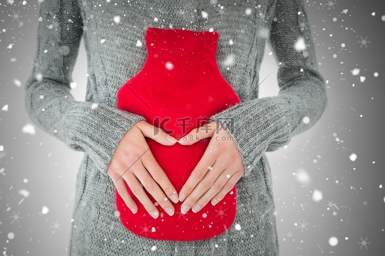 腹部拿着红色热水袋的女人的中段