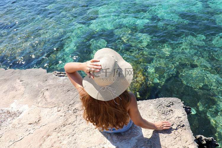 坐在海面悬崖上的年轻女子的夏季
