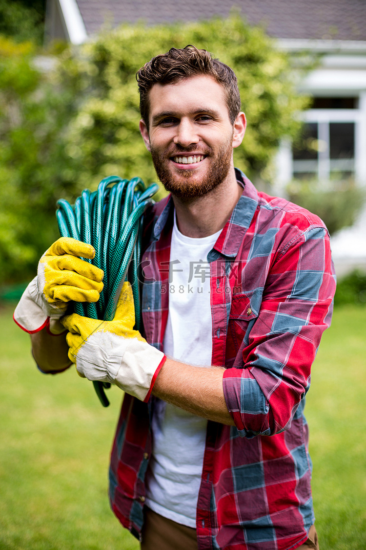 微笑的男人在院子里提着花园软管