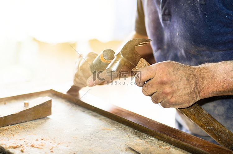 在木制工作台上用凿子和锤子工作