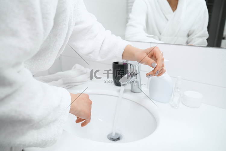 穿着白袍的女人站在水槽边洗手。