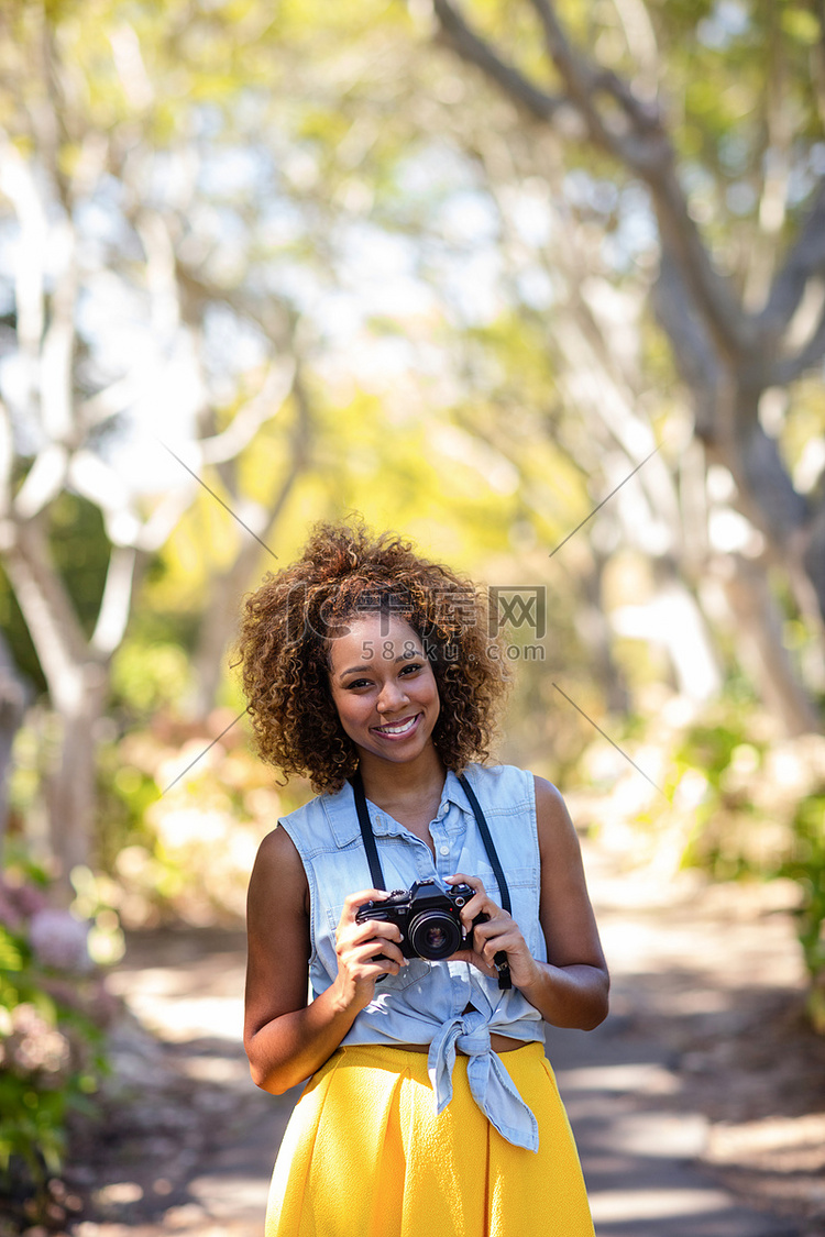 微笑的女人站在数码相机前