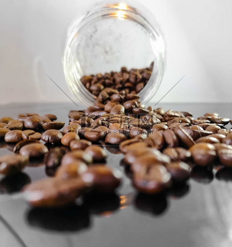 许多咖啡豆躺在从玻璃容器中掉落