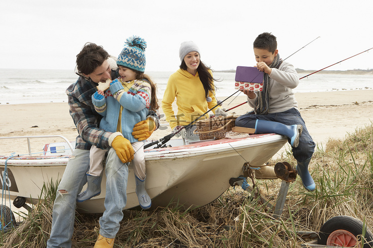家庭组坐在船上用钓鱼竿在冬季海