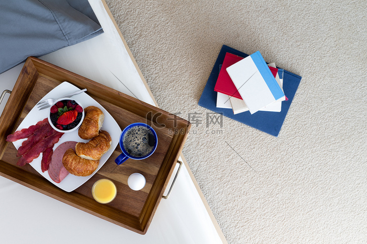床边地板上的书和早餐托盘