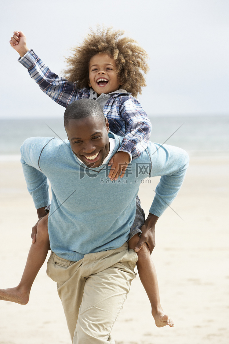 父子俩在沙滩上背驮着玩