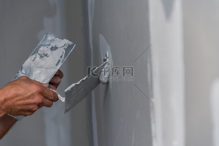 老体力工人用抹墙工具装修房子