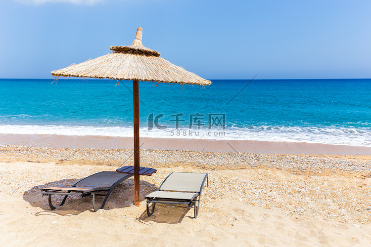 海边沙滩上带躺椅的芦苇沙滩伞