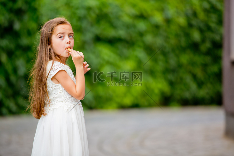 一个穿白裙子的小女孩正在吃冰淇