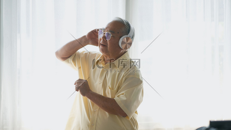 快乐的退休老人戴着耳机听音乐收