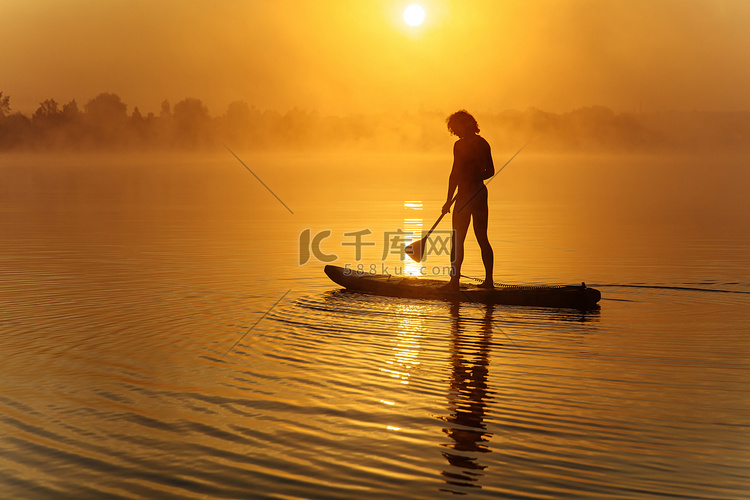 在雾蒙蒙的湖面上划船的健壮男子