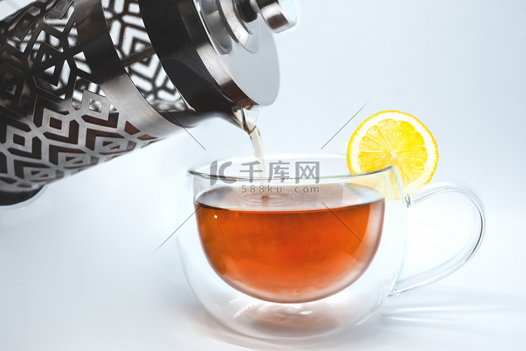 玻璃茶壶将红茶倒入白色隔离的杯