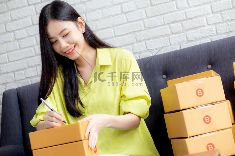 年轻的亚洲女性在家里的包裹箱上