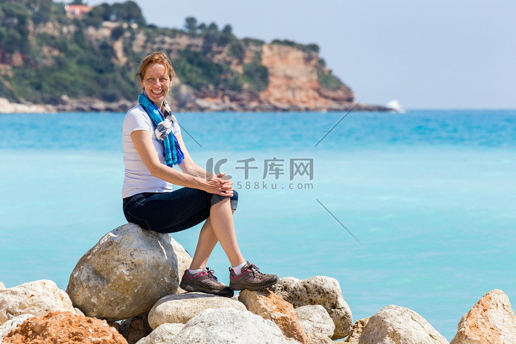 作为游客的欧洲妇女坐在蓝海附近