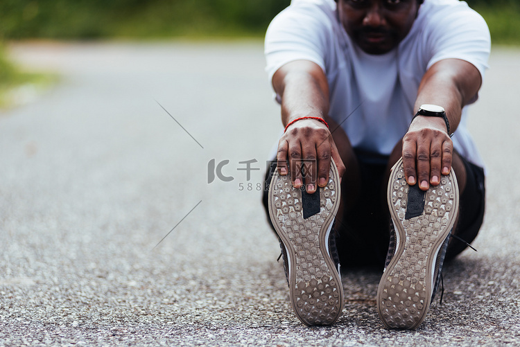 运动跑步者黑人戴手表他坐着拉脚