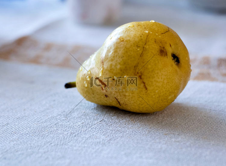 成熟的黄梨躺在桌布上的桌子上