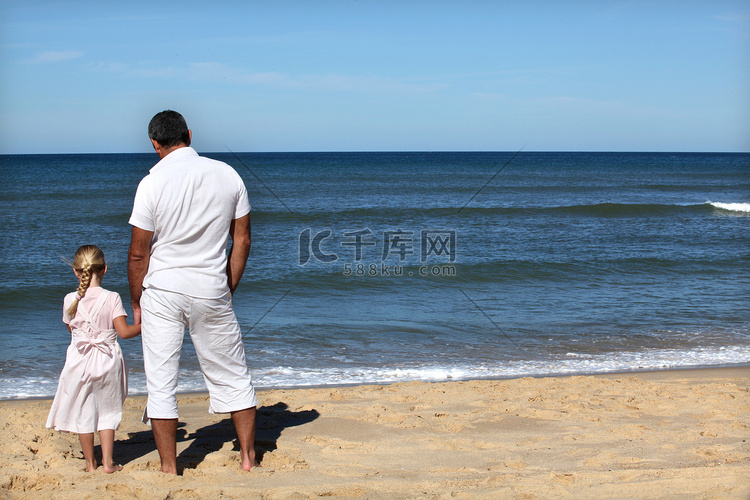 父亲和女儿在海滩上看地平线