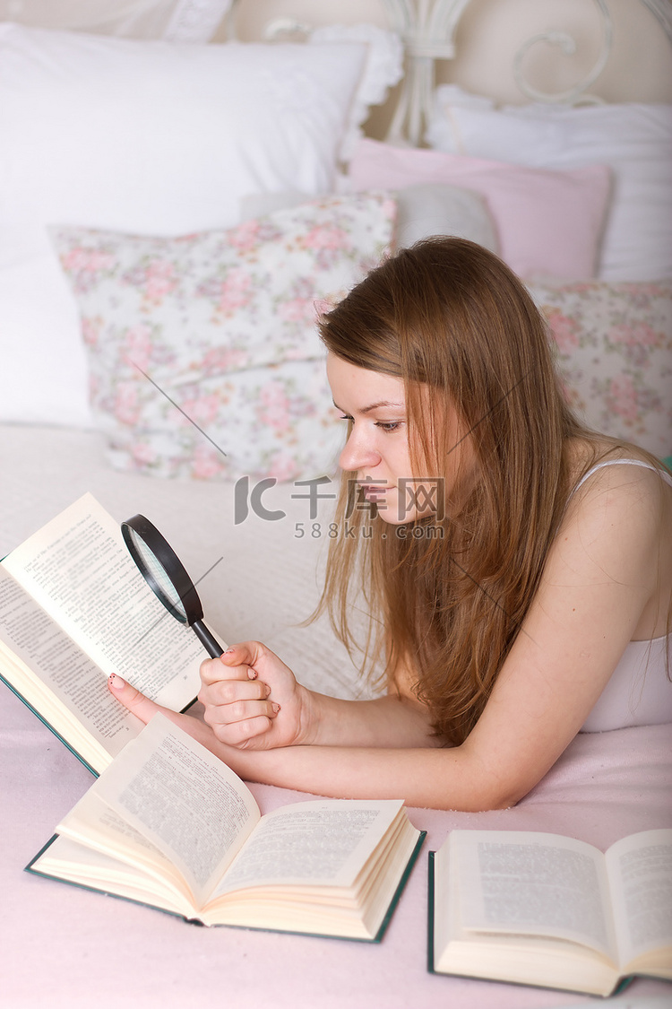 拿着放大镜躺在床上看书的女人