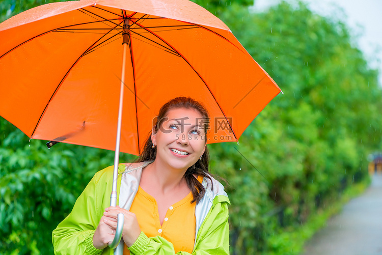 快乐的黑发女郎穿着橙色雨衣的肖
