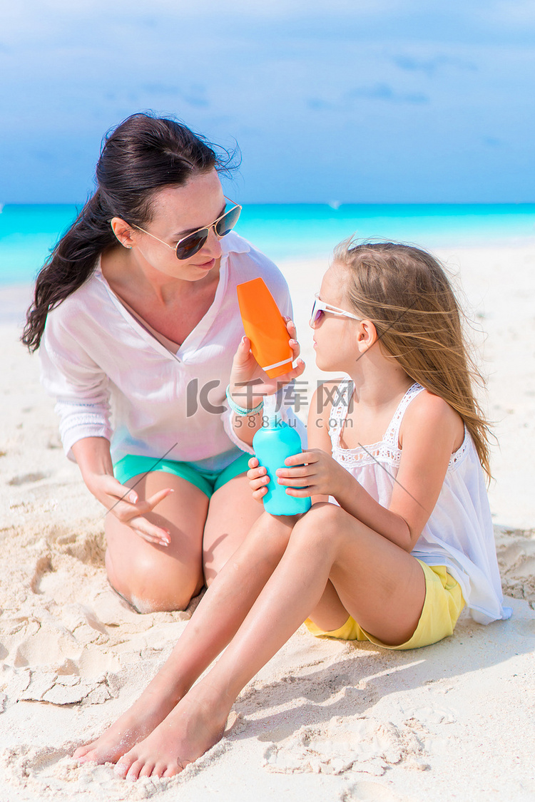有爱心的妈妈在白色沙滩上给孩子