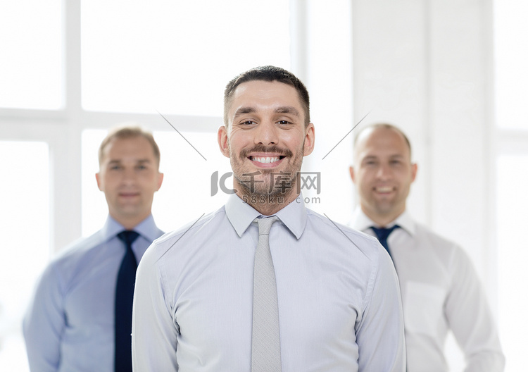 微笑的商人在办公室与团队在后面