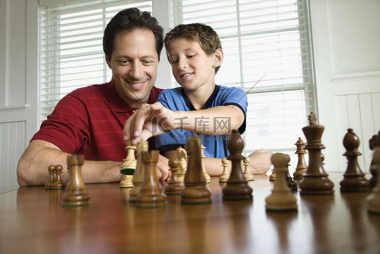 爸爸教儿子下棋。