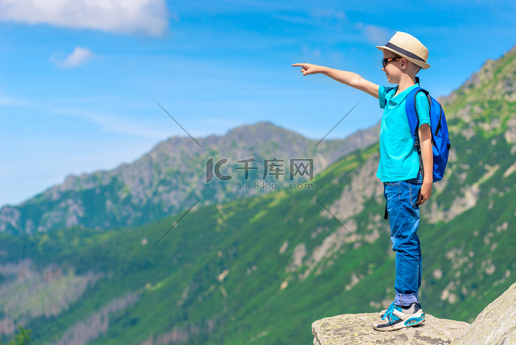 站在岩石上指着一个男孩旅行者的