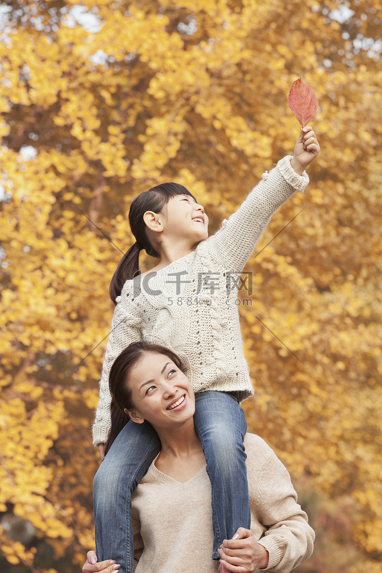 女儿骑在妈妈肩上赏秋叶