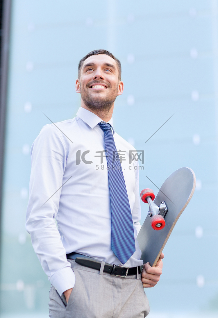 带着滑板在户外微笑的年轻商人
