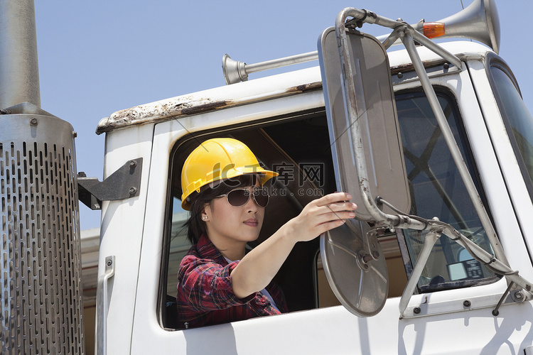 亚洲女产业工人坐在伐木车里调整