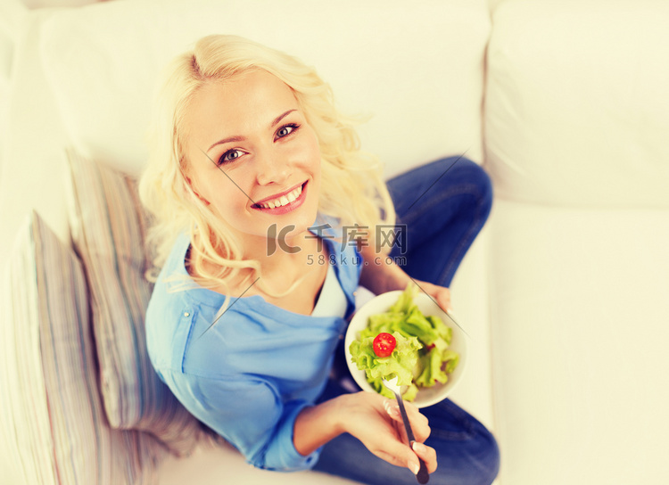 微笑的年轻女人在家吃蔬菜沙拉