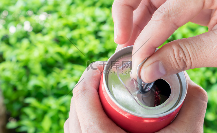 特写女人的手打开可乐罐与自然绿