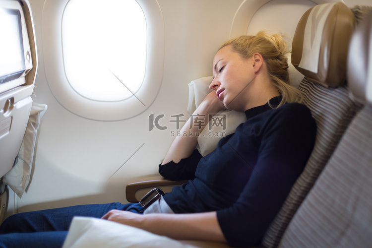 疲惫的金发休闲白种女人在飞机上