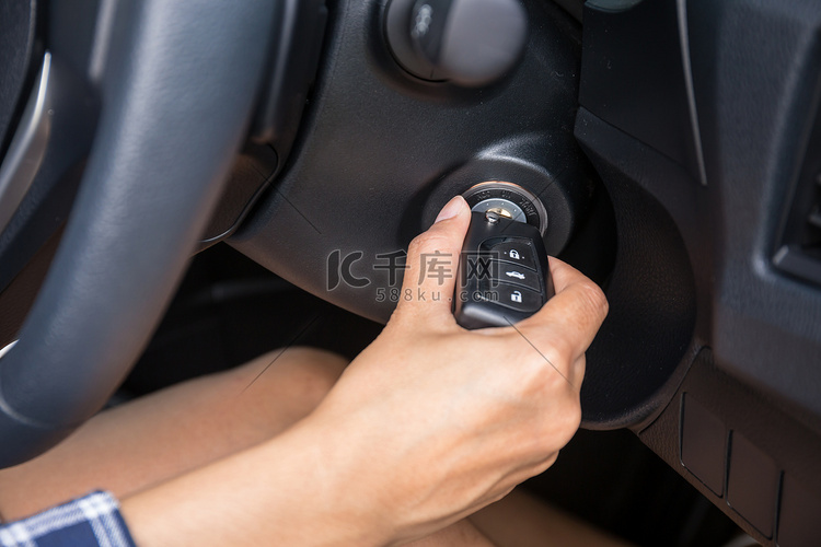 女司机手插入车钥匙和启动引擎。