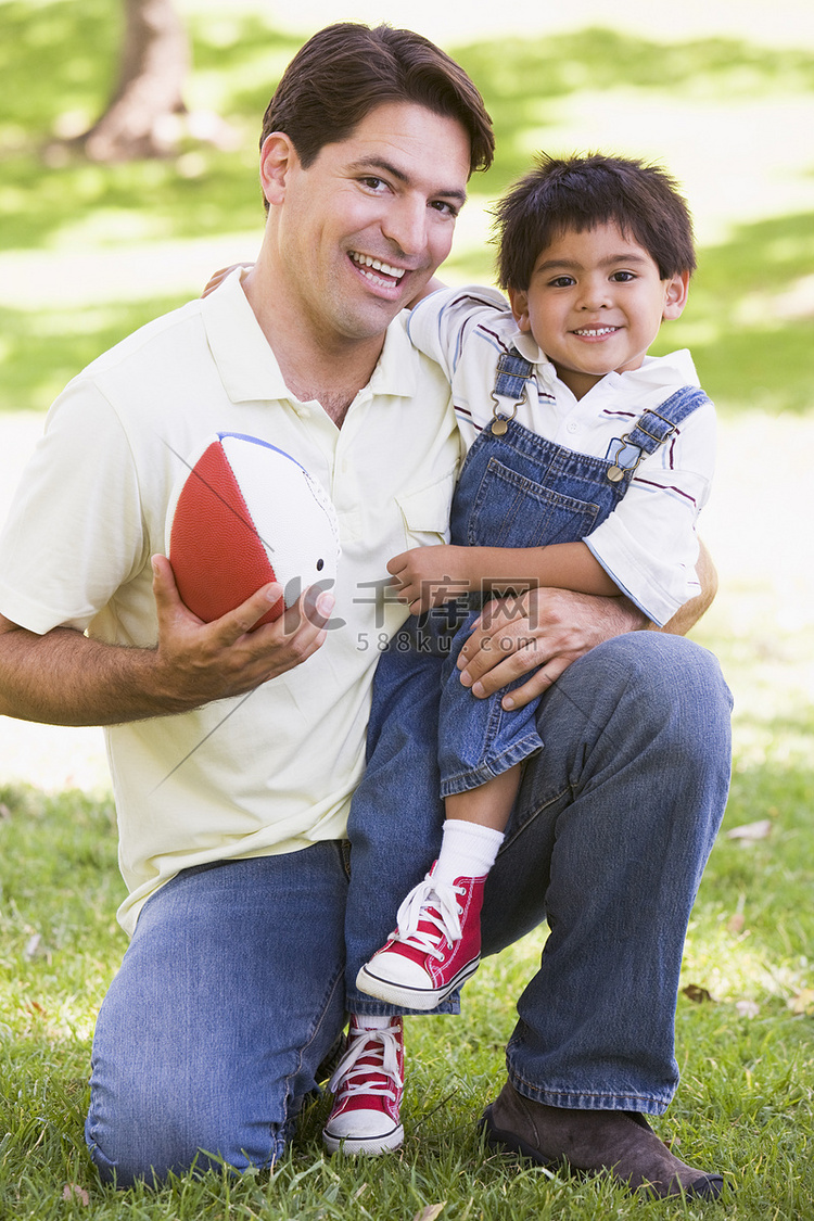 男人和小男孩在户外微笑着踢足球