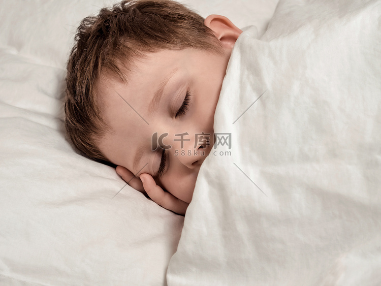 在白色床上睡觉的小男孩