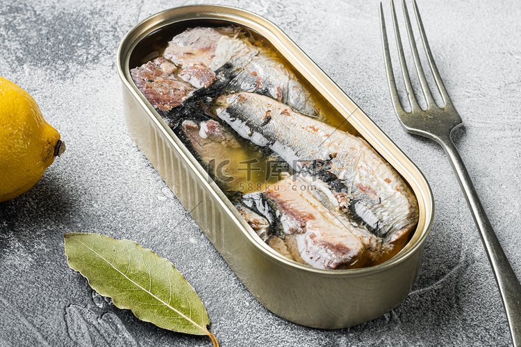灰色石桌背景中的橄榄油沙丁鱼罐