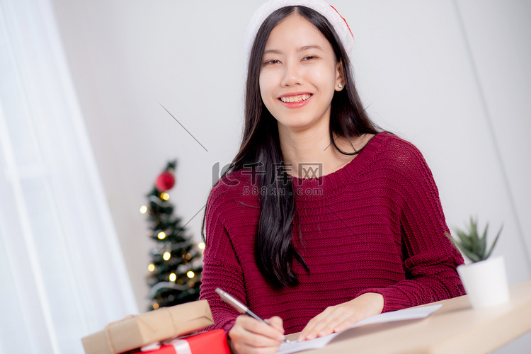 年轻的亚洲女性在圣诞节在家里写