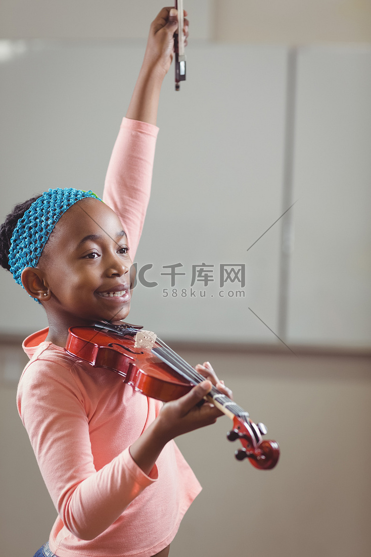 微笑的学生在教室里拉小提琴