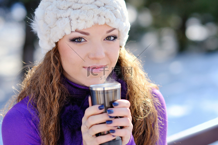 冬天坐在长椅上喝杯咖啡的年轻美