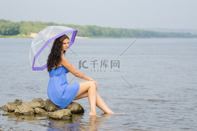 孤独悲伤的年轻女人带着雨伞坐在